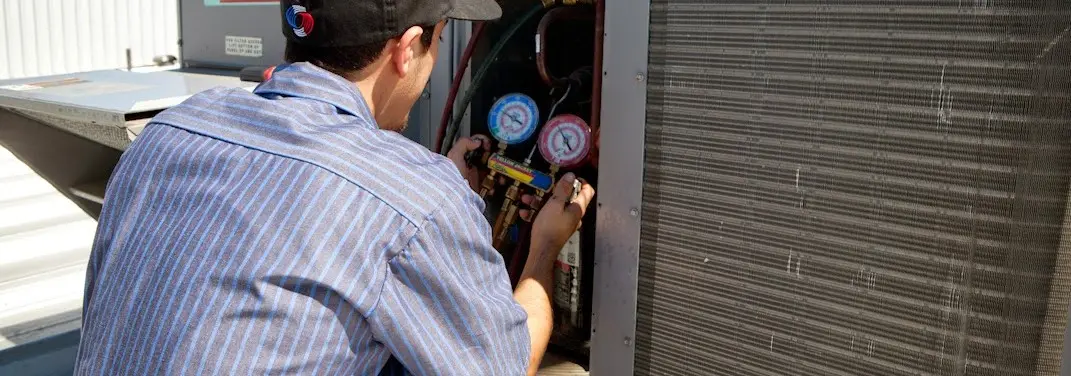 HVAC technician servicing a condenser unit in St. Cloud